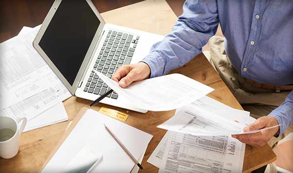 Picture of man organizing paper forms on desk.